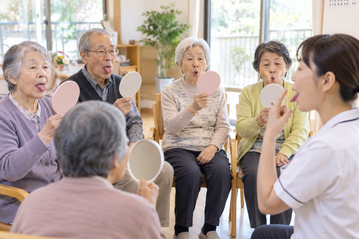 言語聴覚士と一緒に舌の体操をする高齢者グループ